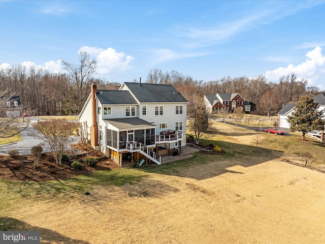 back of house with a sunroom, a chimney, stairway, and a yard