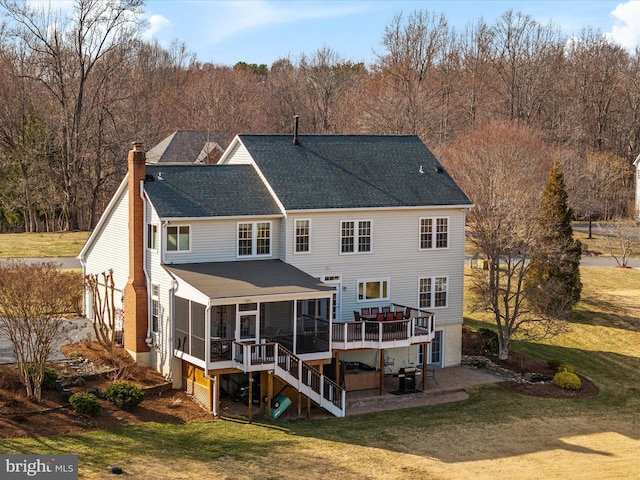 rear view of house featuring a wooden deck, a chimney, roof with shingles, stairs, and a yard