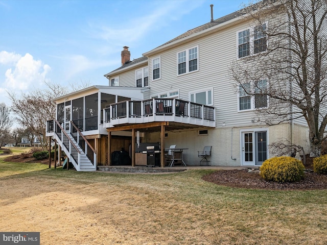 back of property with a sunroom, a lawn, stairway, a chimney, and a patio area