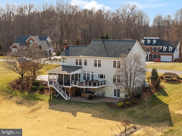 back of property featuring a deck, a sunroom, a lawn, stairway, and a patio area