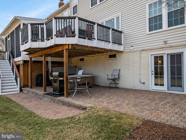 rear view of property featuring stairs, a patio, brick siding, and a deck