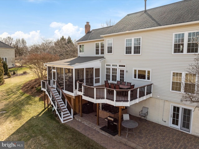 back of house with a sunroom, a chimney, stairway, a yard, and a patio area