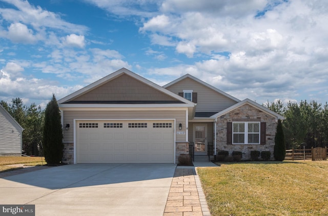 craftsman inspired home with concrete driveway, an attached garage, a front yard, fence, and stone siding