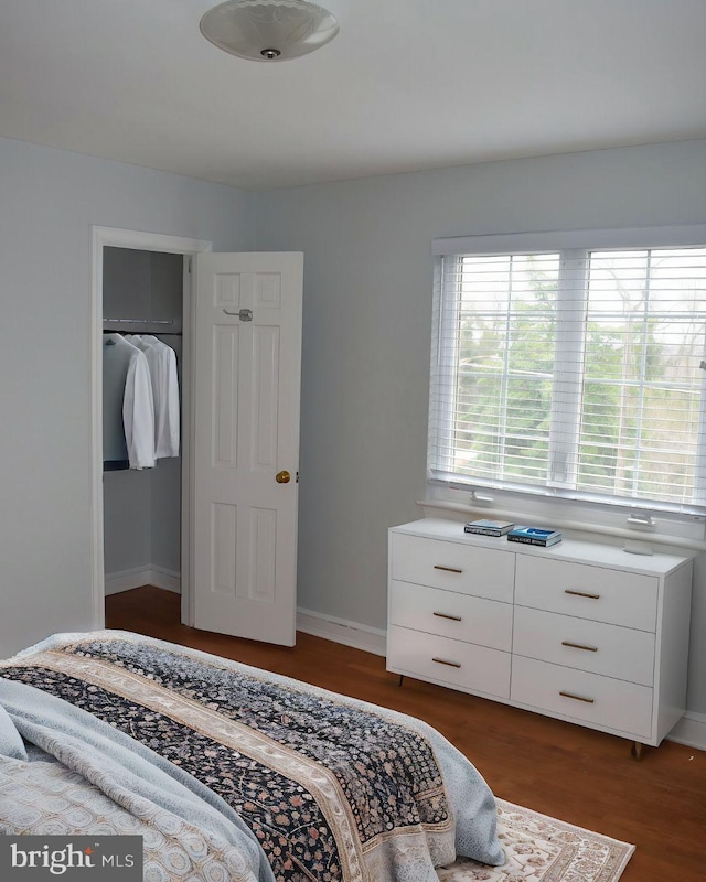 bedroom featuring a closet, baseboards, and dark wood-style flooring