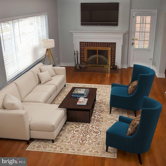 living area featuring a brick fireplace, baseboards, and wood finished floors