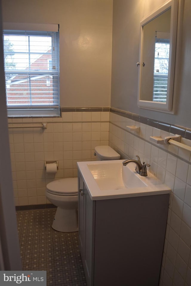 bathroom featuring wainscoting, a healthy amount of sunlight, vanity, and toilet