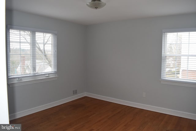 spare room with visible vents, baseboards, and wood finished floors