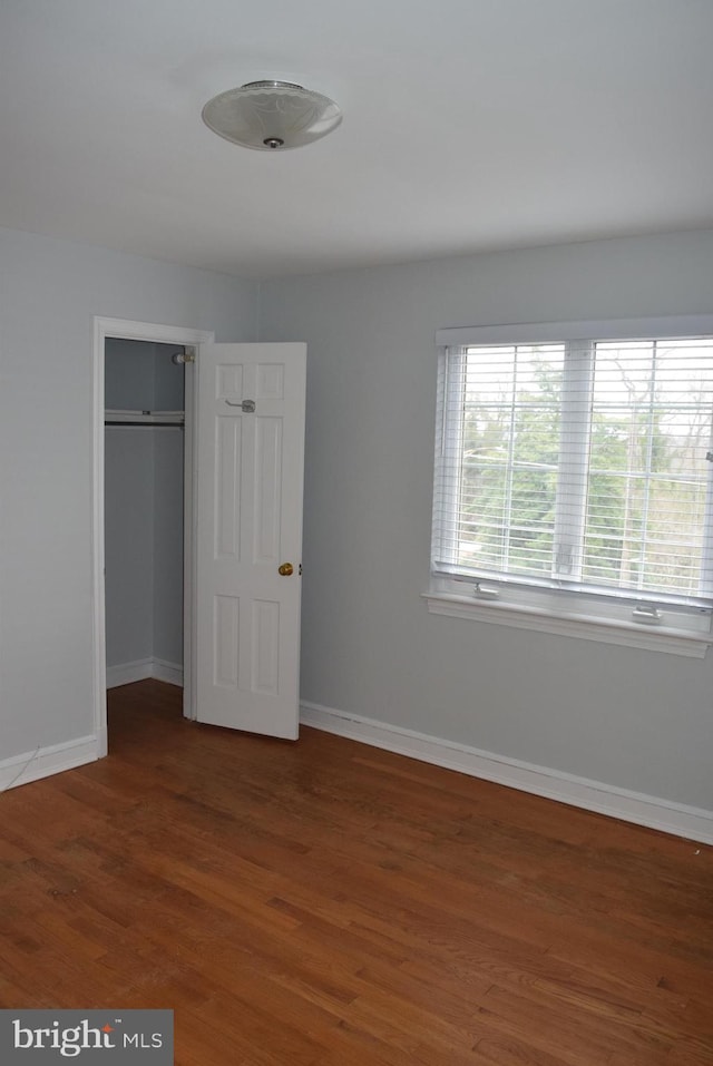 unfurnished bedroom featuring a closet, baseboards, and wood finished floors