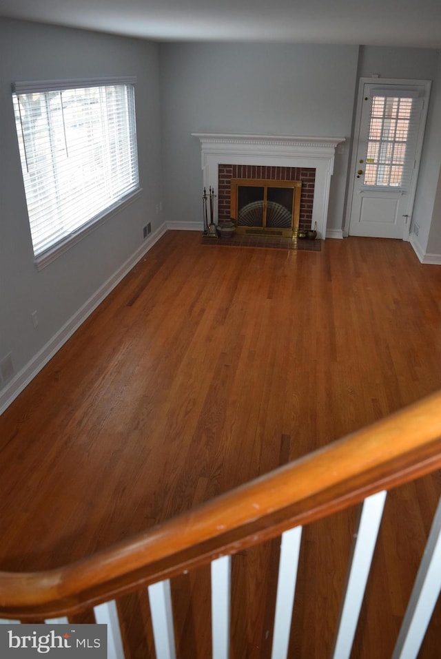 unfurnished living room featuring plenty of natural light, a fireplace, and wood finished floors