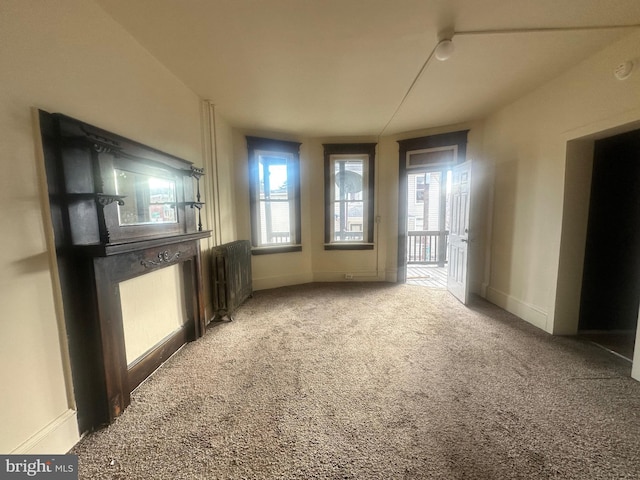 empty room featuring carpet, radiator heating unit, and baseboards