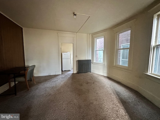 unfurnished living room featuring radiator and carpet