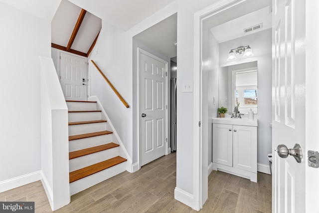 stairway featuring wood finished floors, visible vents, and baseboards