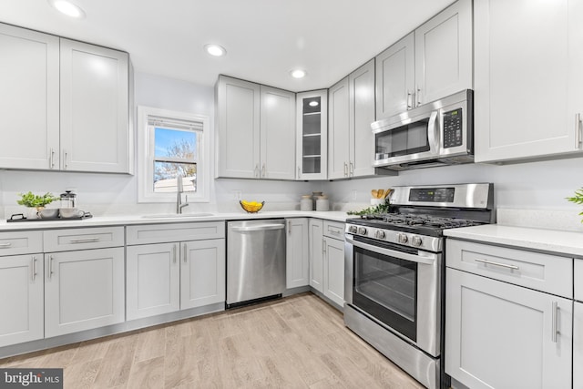 kitchen featuring recessed lighting, a sink, light countertops, appliances with stainless steel finishes, and light wood finished floors