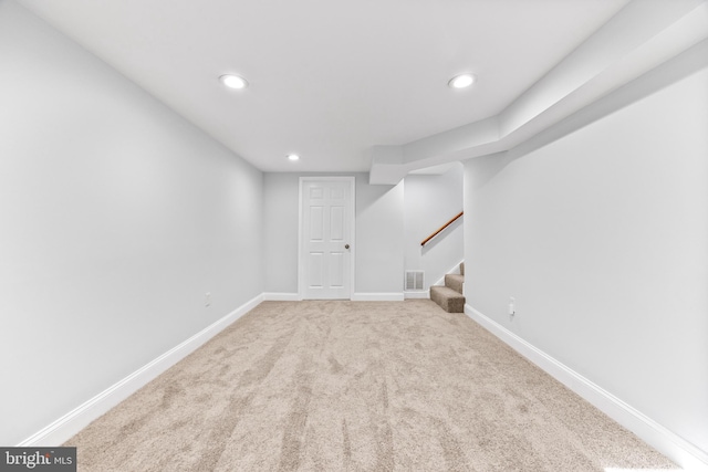 finished below grade area with stairway, carpet, visible vents, and baseboards