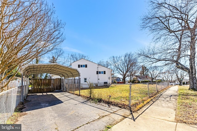 view of side of home with a fenced front yard, driveway, and a carport