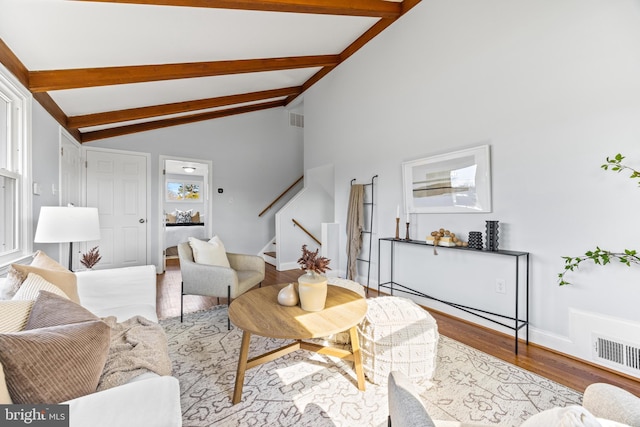 living area featuring visible vents, stairway, lofted ceiling with beams, and wood finished floors