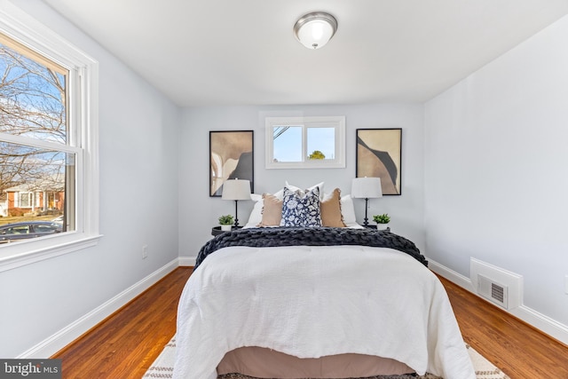 bedroom featuring baseboards, visible vents, and wood finished floors