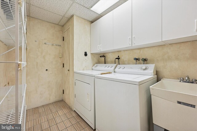 clothes washing area with cabinet space, light tile patterned floors, separate washer and dryer, and a sink