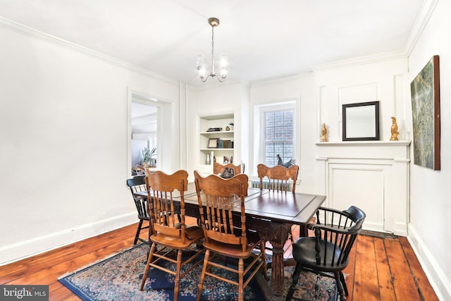 dining space with ornamental molding, wood-type flooring, and an inviting chandelier