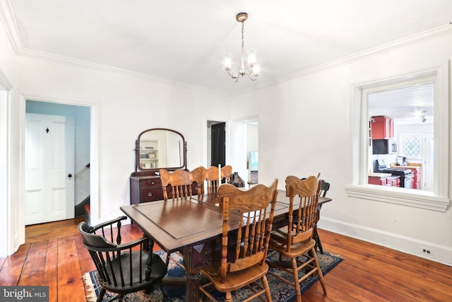 dining space featuring hardwood / wood-style floors, ornamental molding, and a notable chandelier