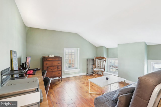 interior space featuring lofted ceiling, radiator heating unit, baseboards, and light wood finished floors