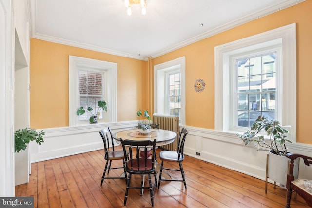 dining space with a healthy amount of sunlight, wood-type flooring, baseboards, and crown molding