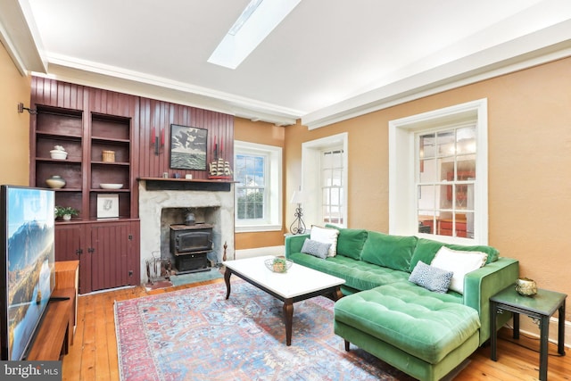 living area featuring a wood stove, a skylight, and wood-type flooring