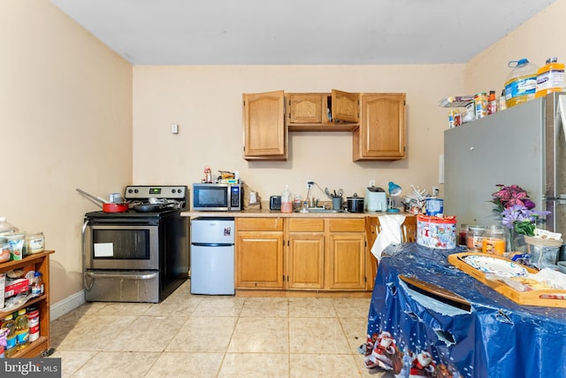 kitchen with stainless steel appliances, light countertops, and light tile patterned floors