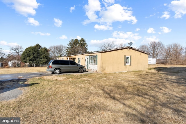 view of property exterior featuring fence and a lawn