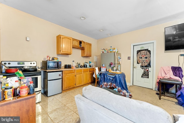 kitchen with light tile patterned floors, light countertops, appliances with stainless steel finishes, and brown cabinetry