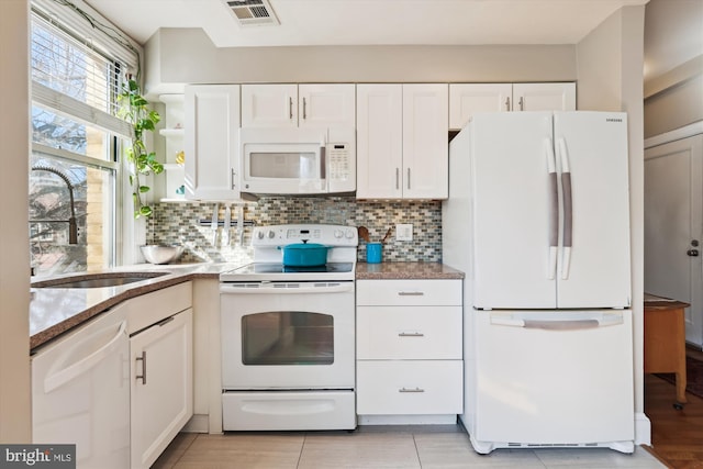 kitchen featuring white appliances, visible vents, white cabinets, and a sink