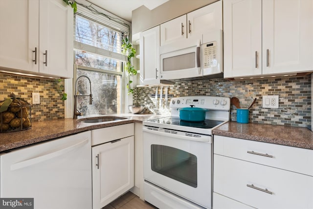 kitchen featuring white appliances, backsplash, white cabinets, and a sink