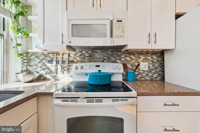 kitchen featuring white appliances, white cabinets, and backsplash