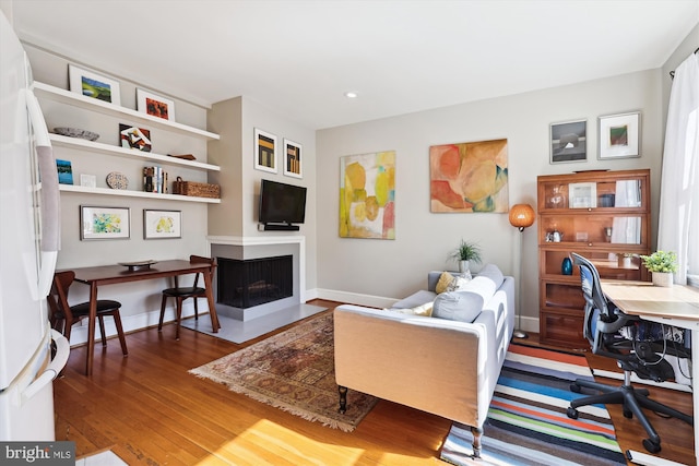 home office with a fireplace with flush hearth, recessed lighting, baseboards, and wood finished floors