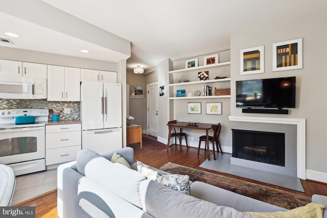 living room with visible vents, baseboards, a fireplace with flush hearth, dark wood-style flooring, and recessed lighting