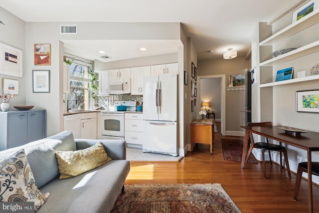 interior space with light wood-style flooring, white appliances, a sink, visible vents, and white cabinets