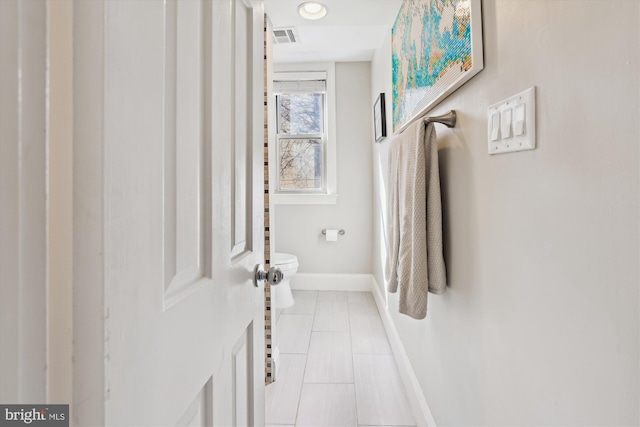 hallway featuring light tile patterned floors, visible vents, and baseboards