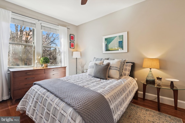 bedroom featuring baseboards, dark wood finished floors, and a ceiling fan