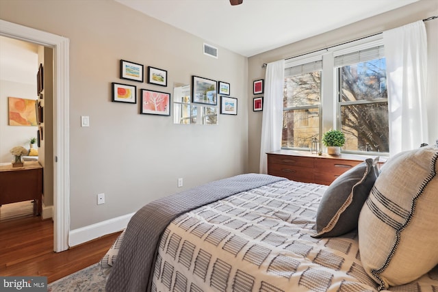 bedroom with wood finished floors, visible vents, and baseboards