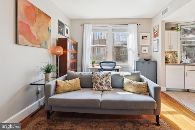 living area featuring visible vents, baseboards, and wood finished floors