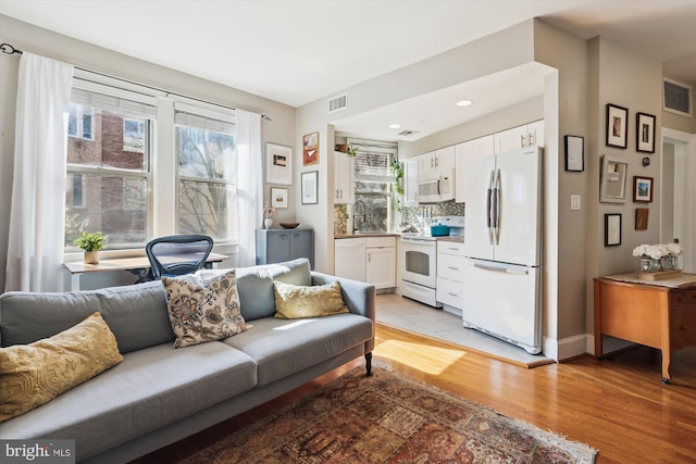 living area with baseboards, visible vents, and light wood-style floors