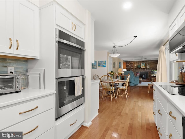 kitchen featuring light countertops, a toaster, light wood finished floors, white cabinetry, and appliances with stainless steel finishes