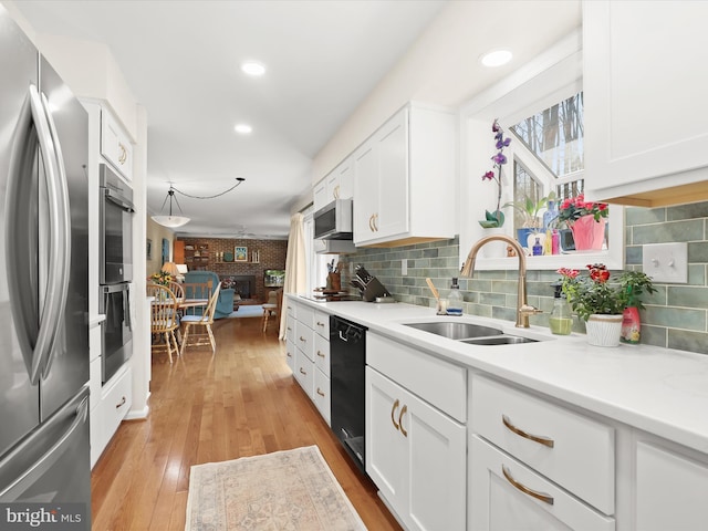 kitchen with white cabinets, light countertops, a sink, light wood-style flooring, and appliances with stainless steel finishes