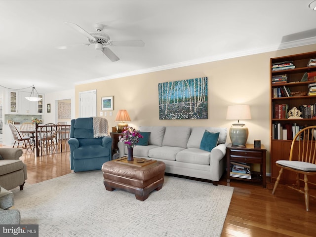 living room with wood finished floors, ceiling fan, and crown molding