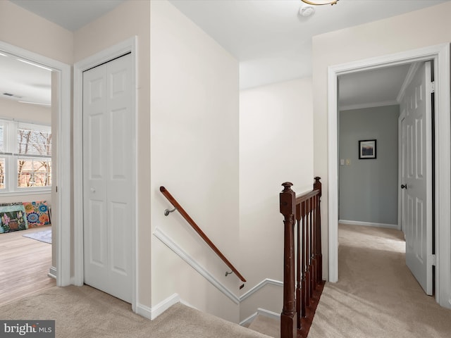 staircase featuring carpet floors, crown molding, visible vents, and baseboards