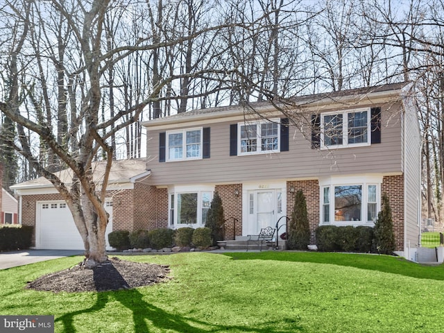 colonial inspired home featuring brick siding, a garage, a front lawn, and concrete driveway