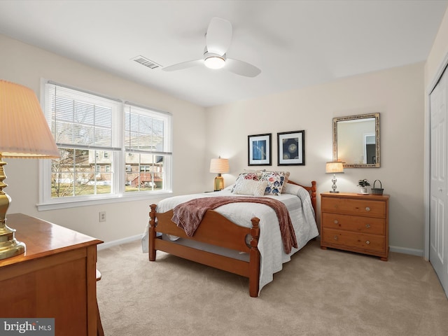 bedroom featuring a closet, ceiling fan, light colored carpet, baseboards, and visible vents
