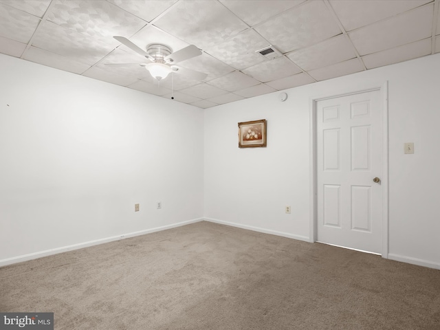 carpeted empty room with visible vents, a paneled ceiling, baseboards, and ceiling fan