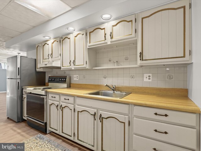 kitchen with tasteful backsplash, a sink, range with electric stovetop, light wood-type flooring, and under cabinet range hood