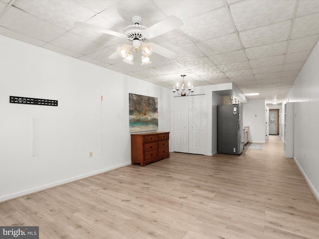 unfurnished room with light wood finished floors, baseboards, and ceiling fan with notable chandelier